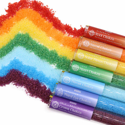 Colorful sand or powder with tubes labeled 'Root Chakra' to 'Crown Chakra' on a white background.