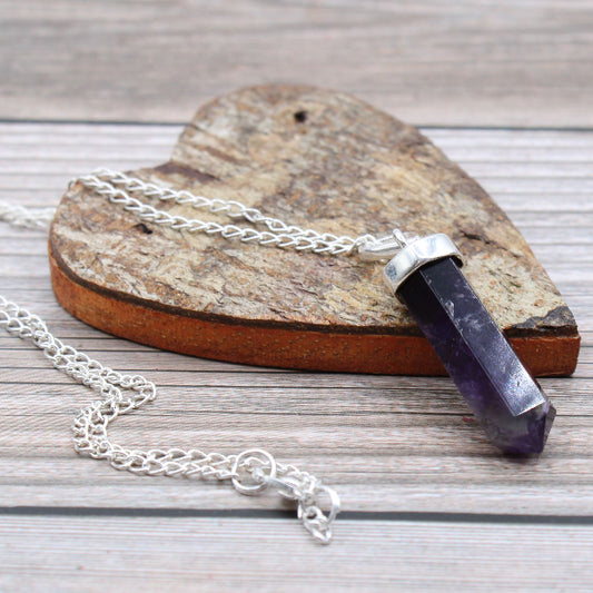 Necklace with a purple crystal pendant on a wooden surface