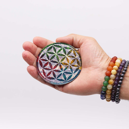 Hand holding a colorful crystal with a geometric design on a white background