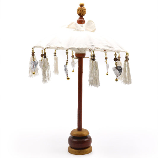 Decorative umbrella with tassels on a wooden stand against a white background