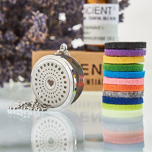 Colorful rubber bands in a stack next to a silver locket with a heart design on a reflective surface.