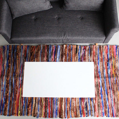 Multicolored woven rug with a white card on top, placed in front of a gray sofa.