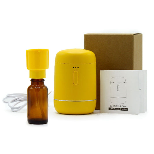 Yellow essential oil diffuser with brown bottle and packaging on a white background