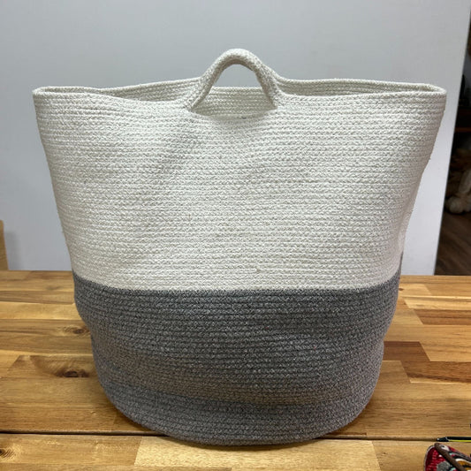Woven basket with two-tone design on a wooden surface