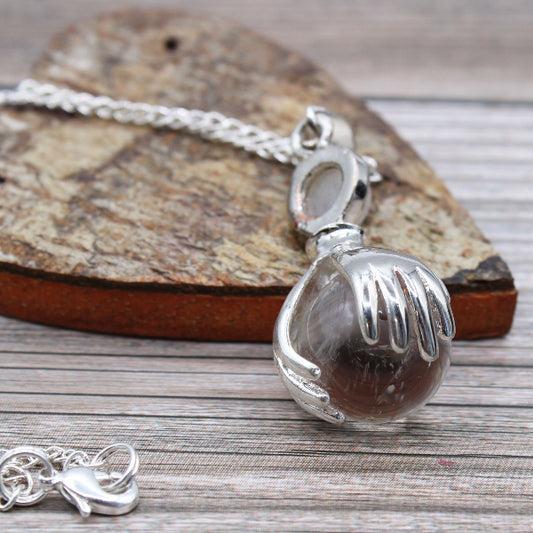Silver pendant with a brown stone on a wooden surface