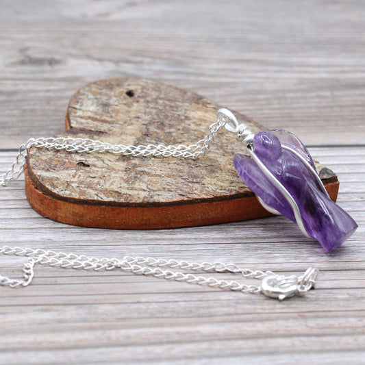 Necklace with a purple crystal pendant on a wooden heart-shaped block