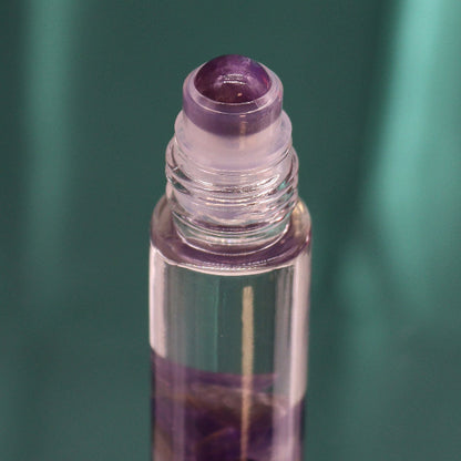 Roll-on bottle with purple cap and clear body on a green background
