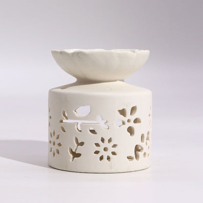 White ceramic oil burner with floral cutout design on a light gray background