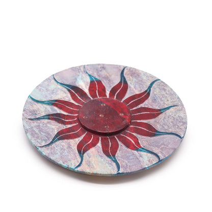 Round decorative plate with a red sun design on a white background