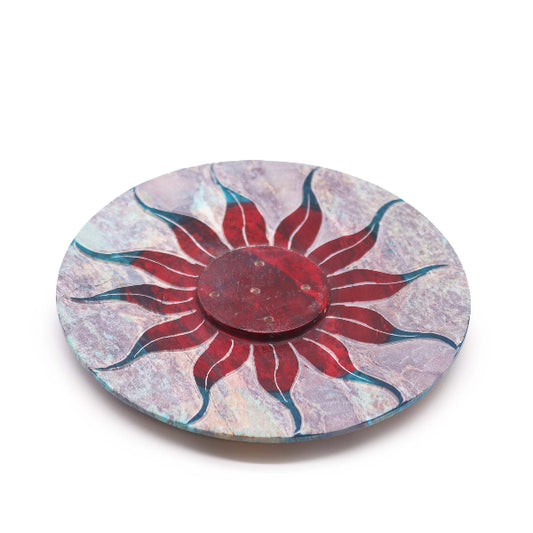 Round decorative plate with a red sun design on a white background