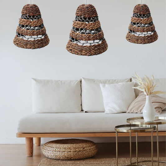 Three woven pendant lights hanging above a white sofa with decorative pillows and a small table.
