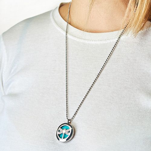 Person wearing a necklace with a circular pendant on a plain white background