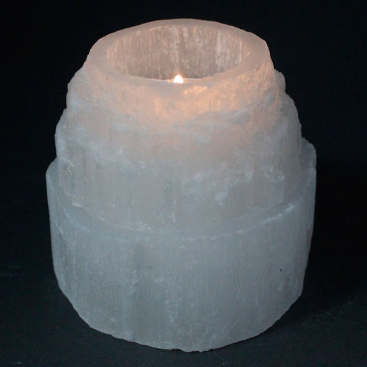 Candle in a textured stone holder on a black background