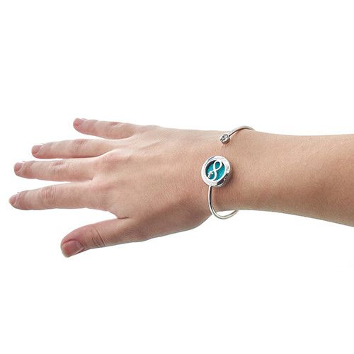 Hand wearing a silver bracelet with a blue circular charm on a white background