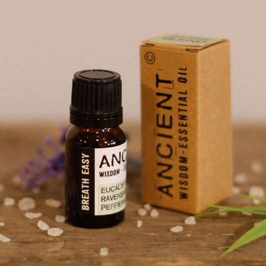 Bottle of essential oil with packaging labeled 'Ancient Wisdom' on a wooden surface.