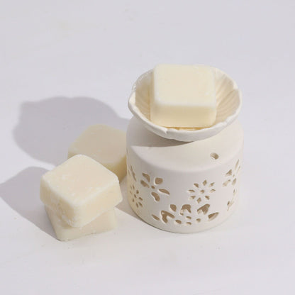 White ceramic container with cut-out design holding a bar of soap on a light background