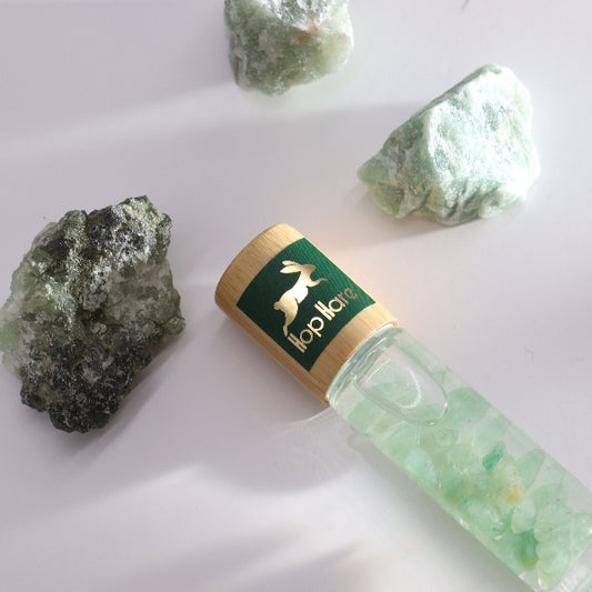 Green crystal bottle with gold cap and visible brand logo on a white background