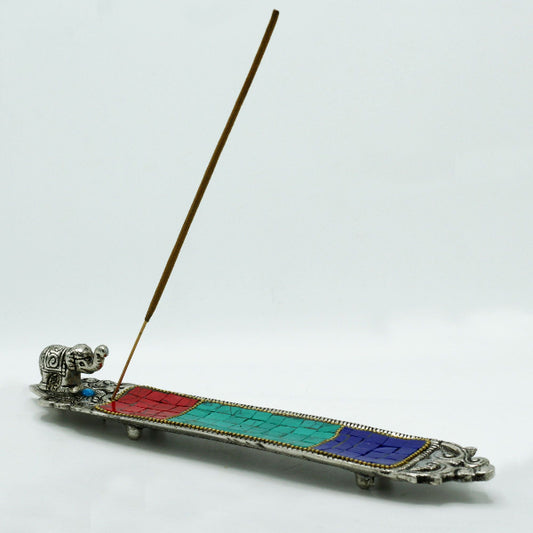 Decorative incense holder with colorful sections and a incense stick on a white background
