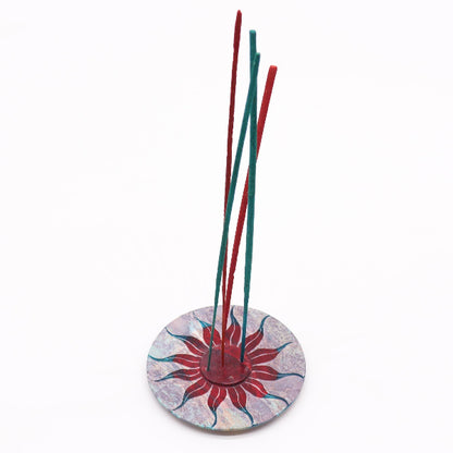 Incense sticks in a decorative holder with a colorful base on a white background