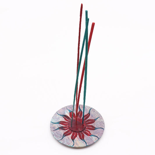 Incense sticks in a decorative holder with a colorful base on a white background
