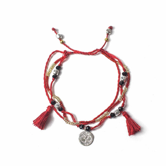 Red bracelet with tassels and a coin charm on a white background