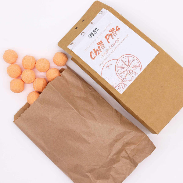 Open brown paper bag with orange balls and a branded box on a white background