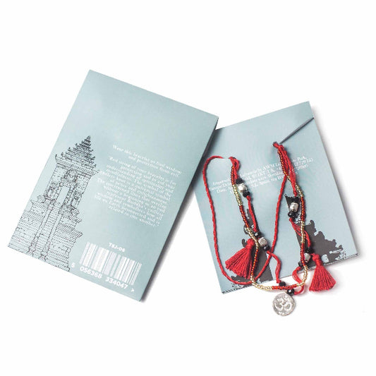 Bracelet with red strings and charms on a branded card