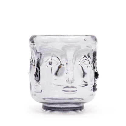 Clear glass tumbler with face design on a white background
