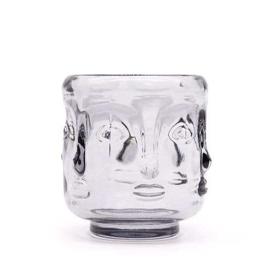 Clear glass tumbler with face design on a white background