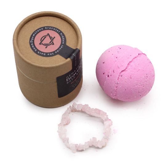Pink bath bomb with a brown paper container and a pink bracelet on a white background