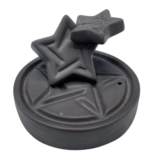 Black decorative object with star designs on a white background
