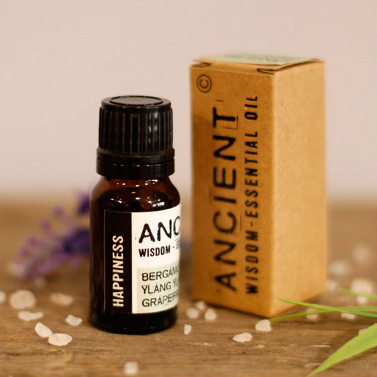 Essential oil bottle and box labeled 'Ancient Wisdom' on a wooden surface with blurred background
