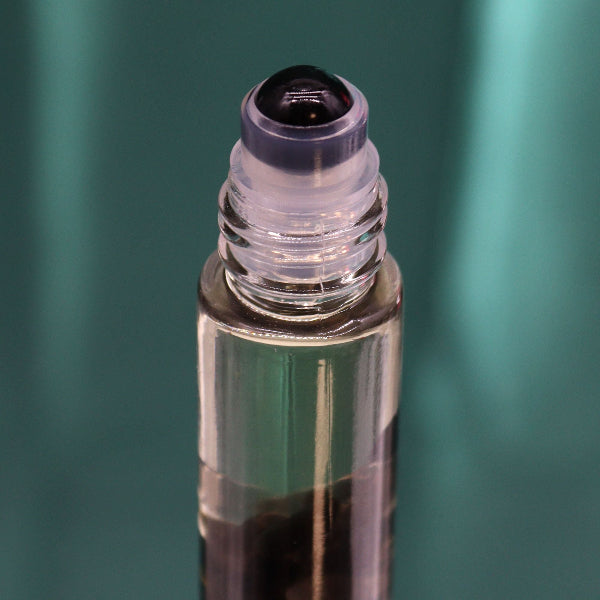 Close-up of a clear rollerball pen with a black cap on a green background
