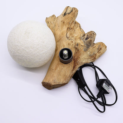 Wooden lamp base with a white spherical lampshade and power cord on a white background