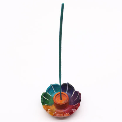 Colorful incense holder with a single green incense stick on a white background
