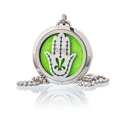Silver locket with green background and white design on a white background