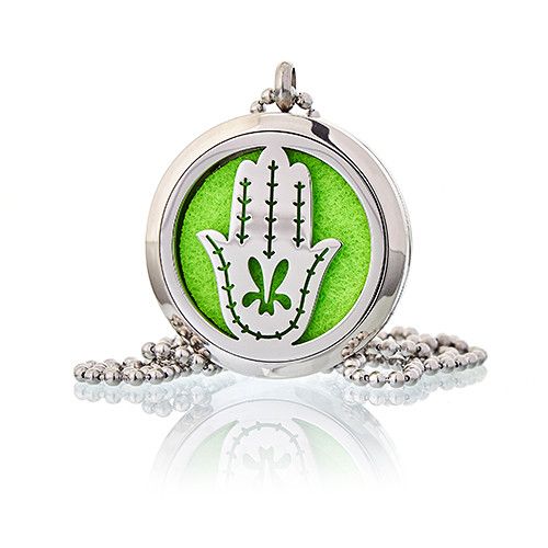 Silver locket with green background and white design on a white background