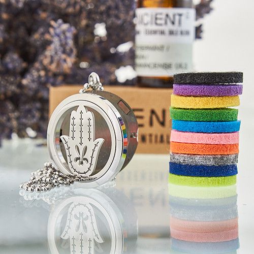 Decorative locket with hamsa design and colorful hair ties on a reflective surface.
