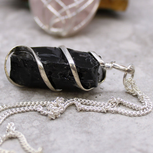 Black stone pendant with silver chain on a gray surface
