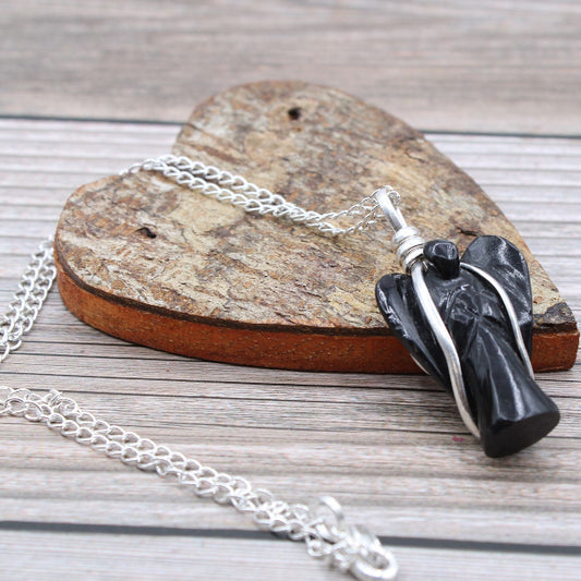 Necklace with a black and silver pendant on a wooden heart-shaped block