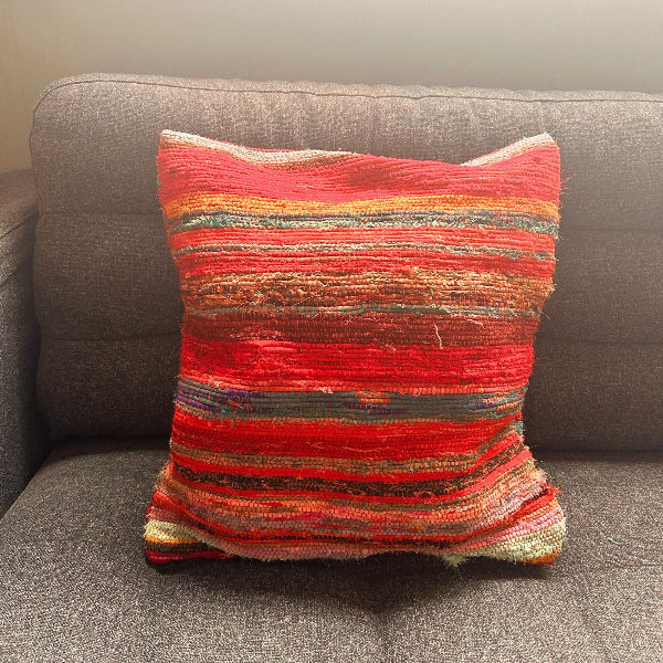 Multicolored striped pillow on a gray sofa