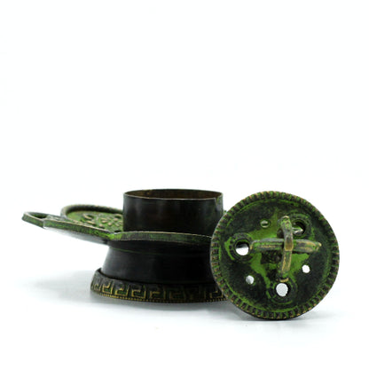 Decorative metal object with green patina on a white background