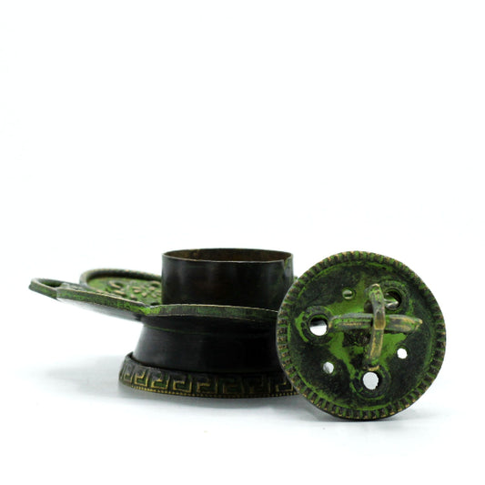 Decorative metal object with green patina on a white background