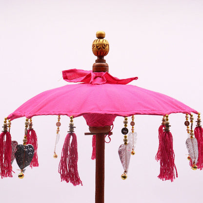 Decorative pink umbrella with tassels and beads on a white background