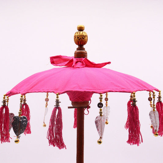 Decorative pink umbrella with tassels and beads on a white background