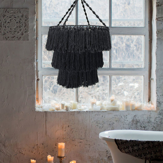 Black fringe chandelier hanging in a bathroom with candles and a window.