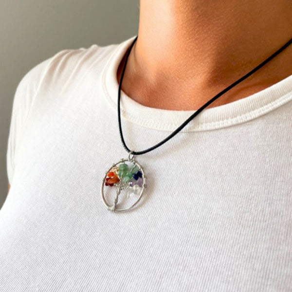 Necklace with a tree of life pendant worn by a person on a plain background