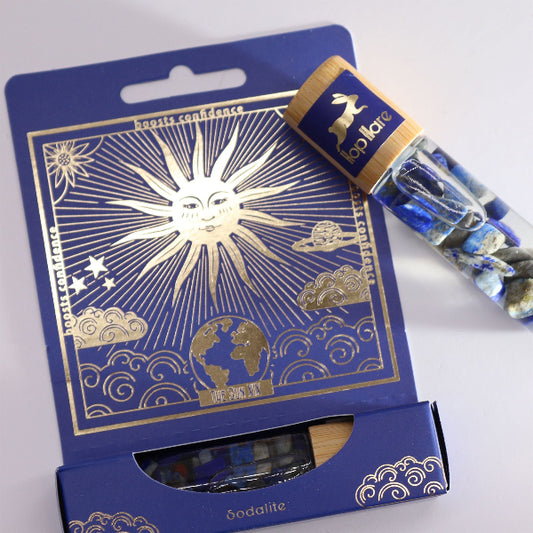 Blue packaging with gold celestial design, featuring a crystal and a card on a white background