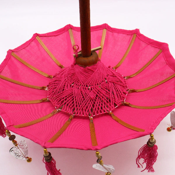 Pink decorative umbrella with wooden handle and tassels on a white background