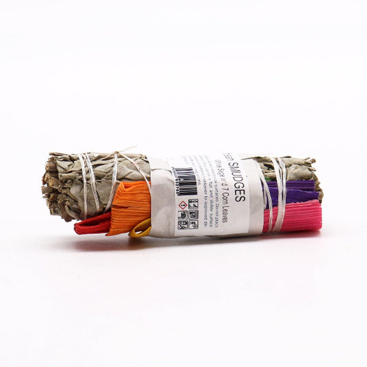 Rolled sage smudge stick with colorful labels on a white background
